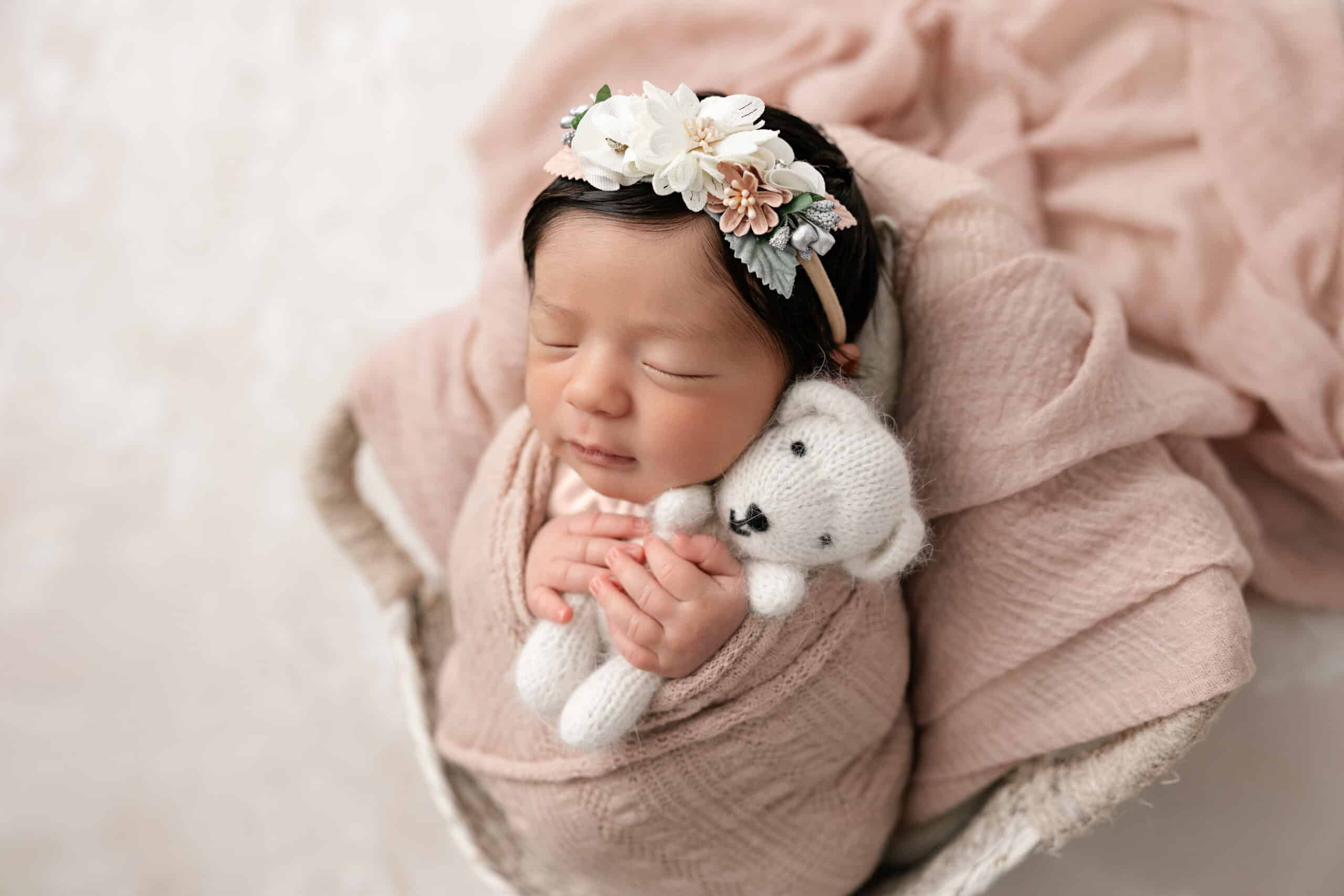 Image by Stephanie Schnautz: a baby posed in swaddle holding bear