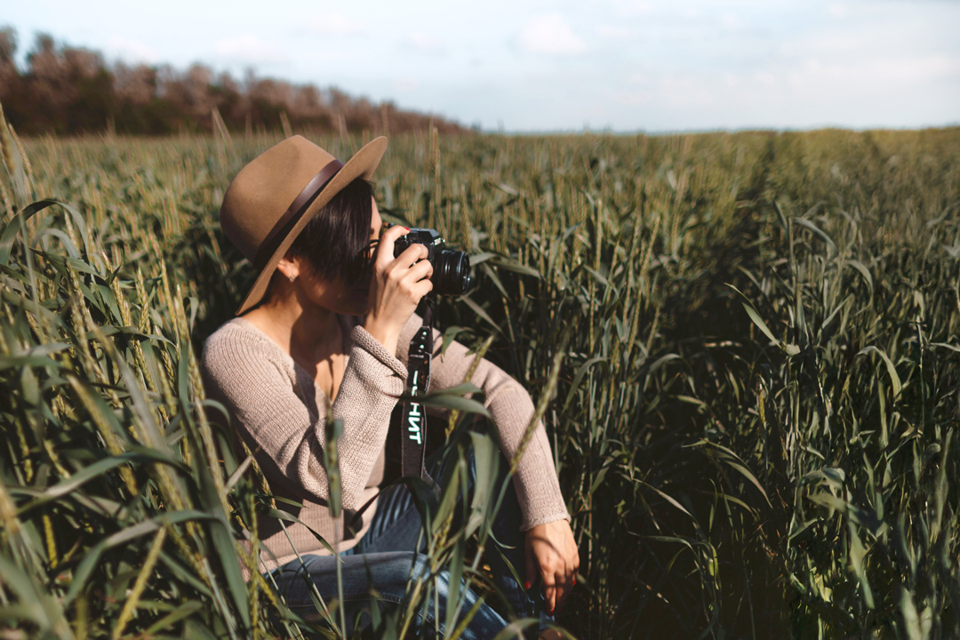 woman sitting in grass looking through camera